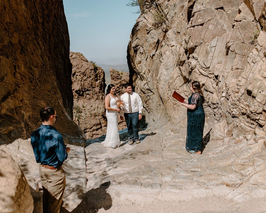 Bride and Groom listening to officiant in canyon