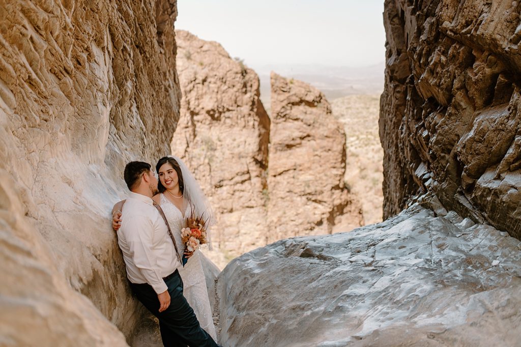 Bride and Groom leaning against canyon wall