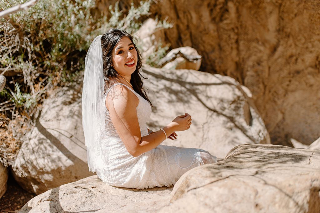 Bride sitting on rock after elopement