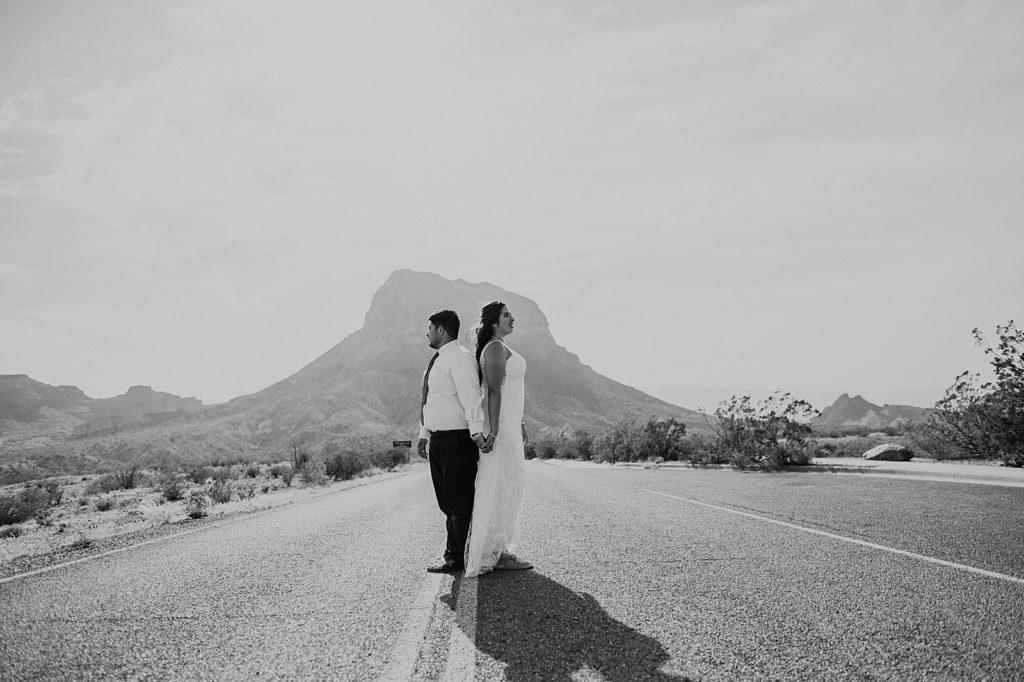 B&W Bride and Groom back and back on the empty road