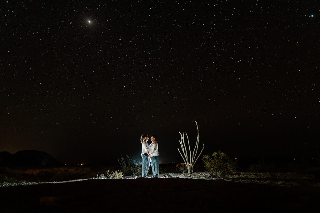 illuminated Bride and Groom hand in hand out in the desert at night