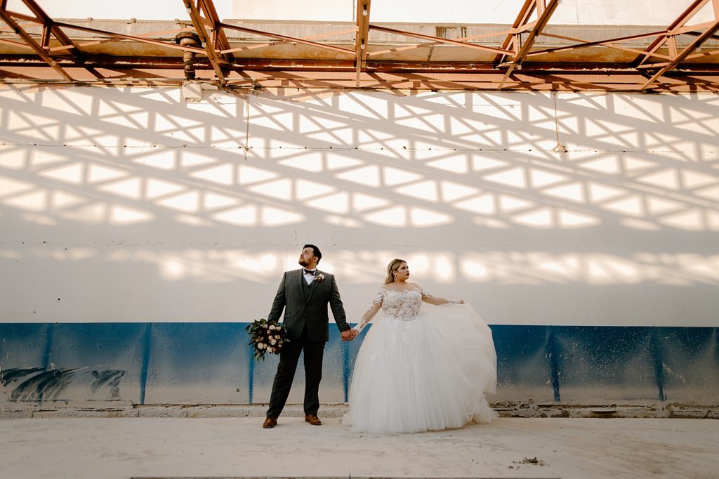 Bride and Groom holding hands and posing in construction area