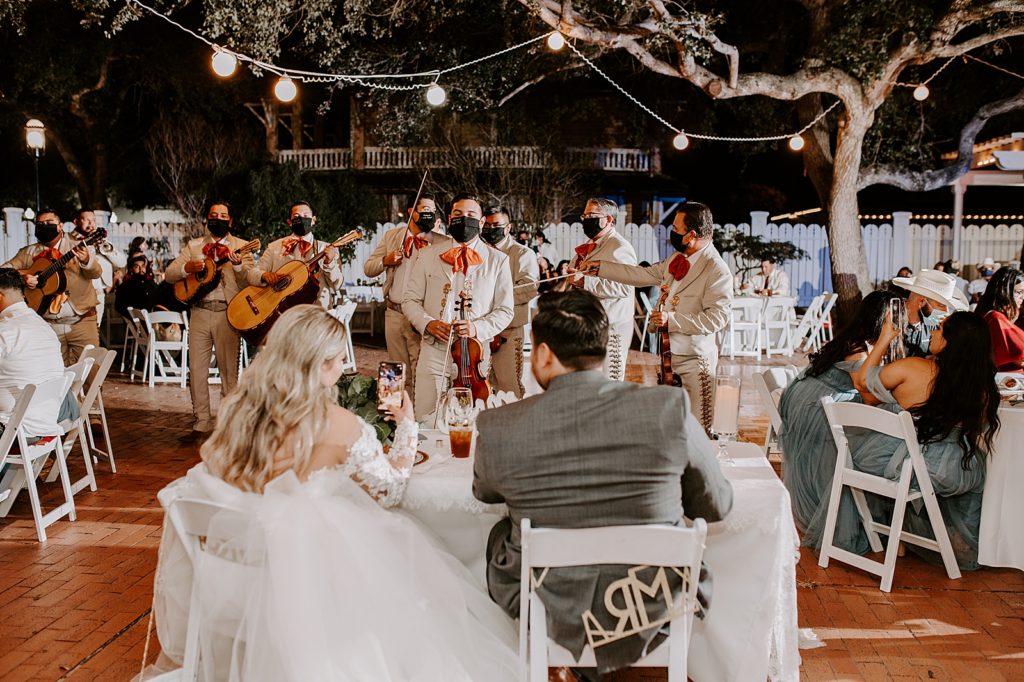 Bride and Groom sitting at sweetheart table with Mariachi band in front of them