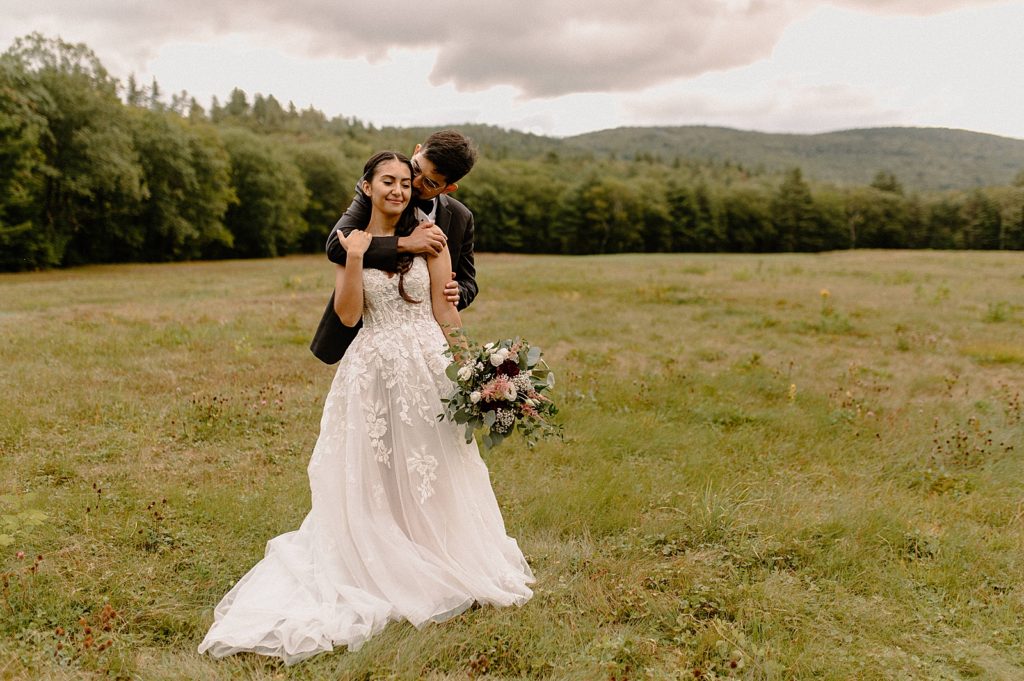 Groom holding Bride out on grassy field