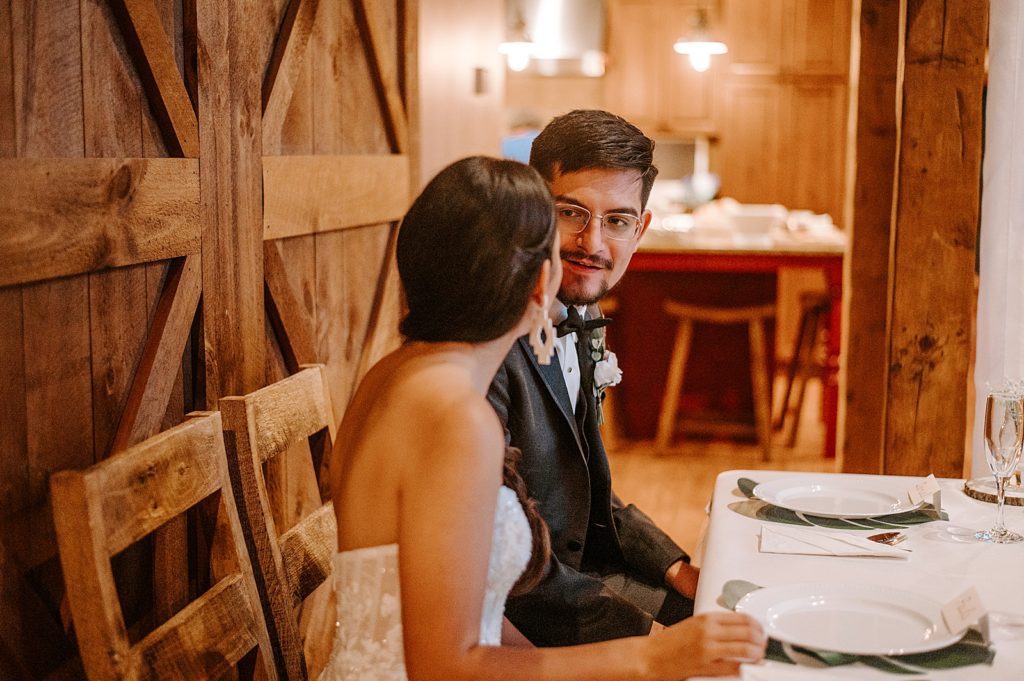 Bride and Groom looking at each other sitting at sweetheart table