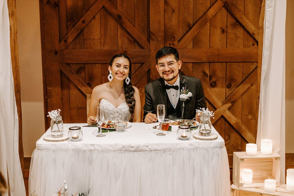 Bride and Groom sitting at sweetheart table with dinner plates