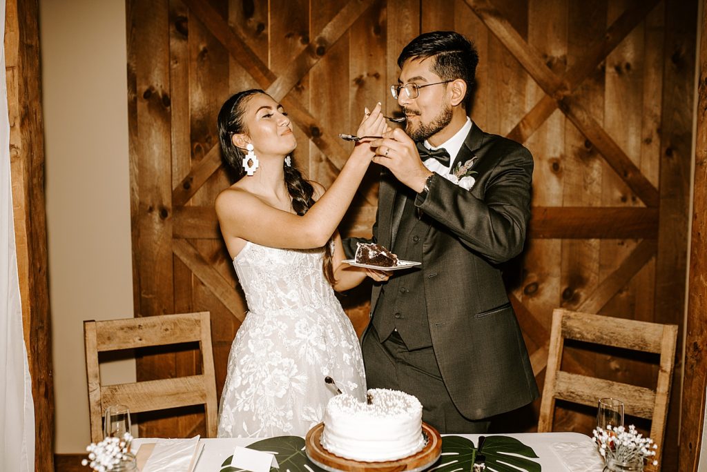 Bride and Groom feeding each other a bite of cake at sweetheart table