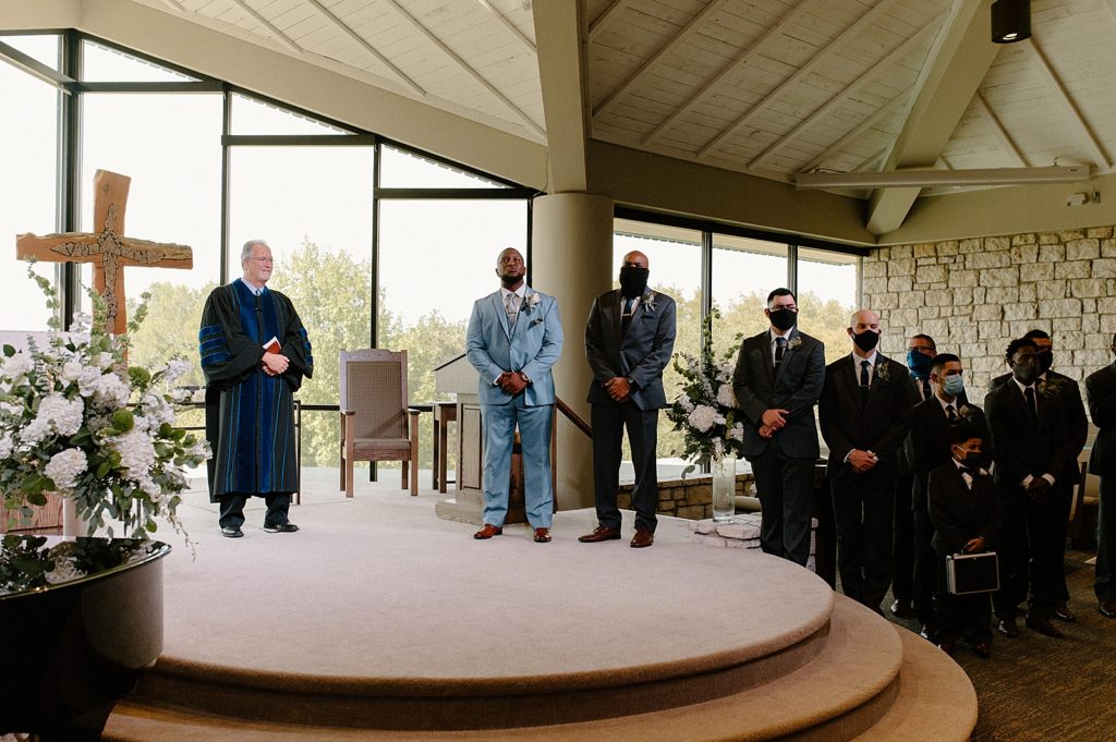Groom awaiting Bride with groomsmen in church with officiant