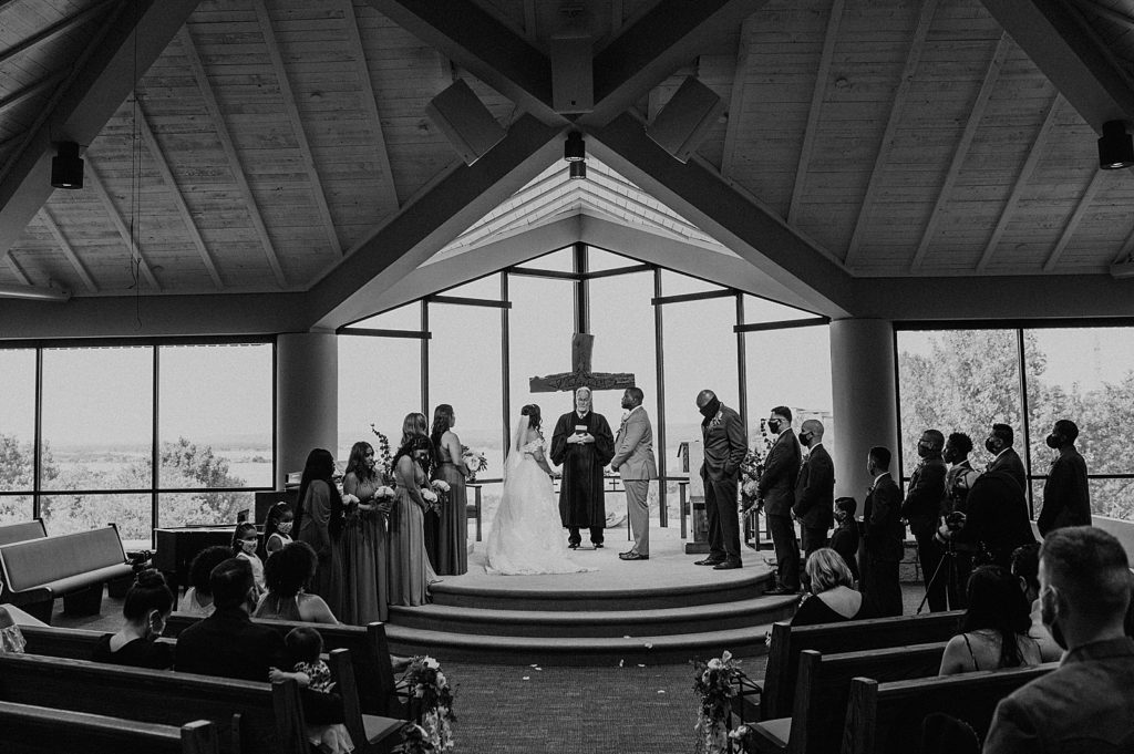 B&W wide shot of Bride and Groom at the alter with wedding party 