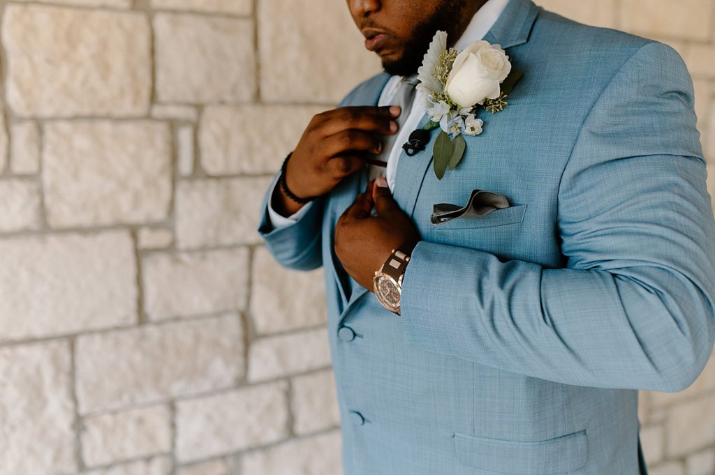 Closeup of Groom adjusting his shirt and ready in light blue suit