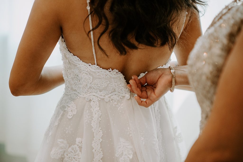 Closeup of mother zipping wedding dress up