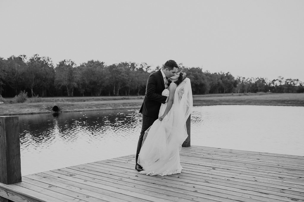 B&W Bride and Groom kissing on dock by calm water