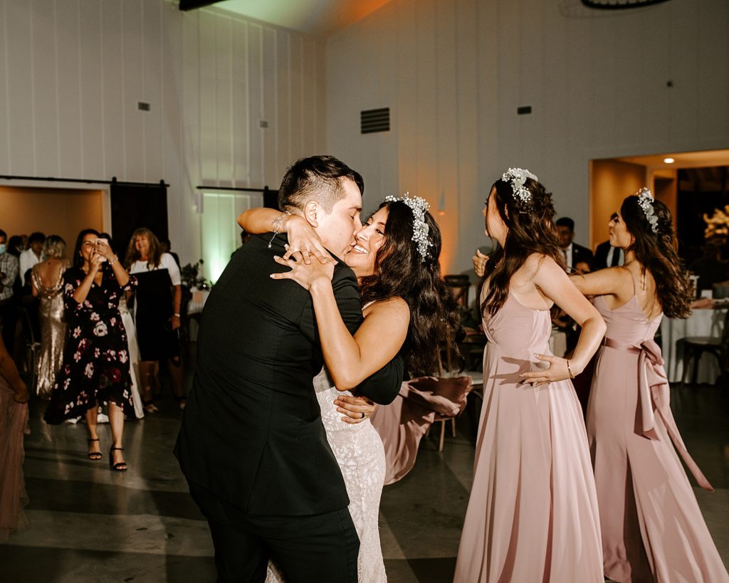 Groom holding Bride and kissing her on dance floor at Reception