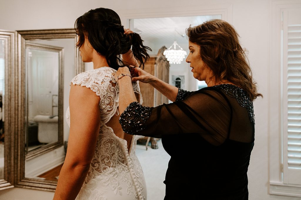Mother helping Bride button up wedding dress