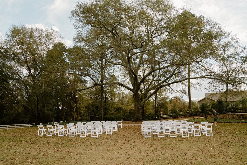Detail shot of white folding chair in front of trees for Ceremony