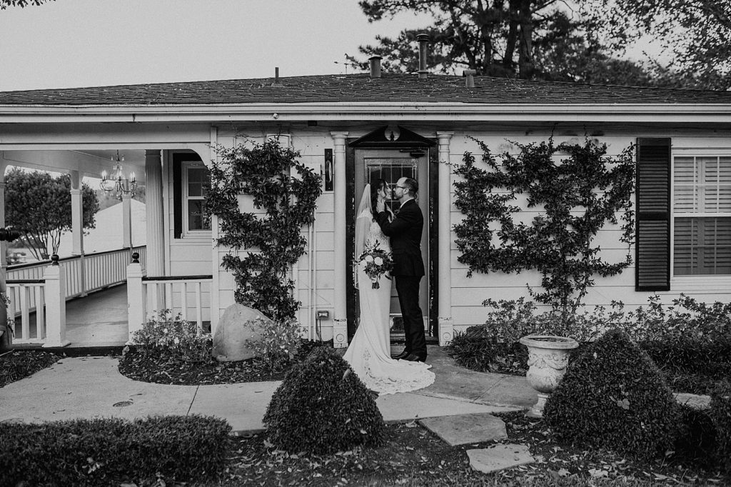 B&W Bride and Groom holding each other in front of house
