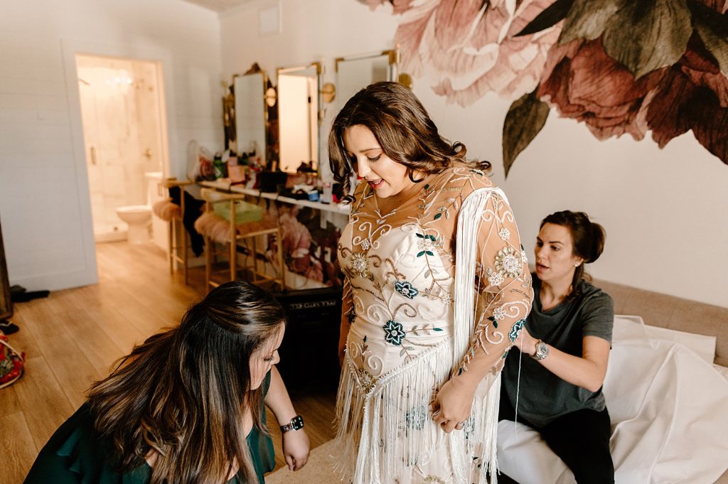 Bride getting ready getting help by Bridesmaids to put on dress