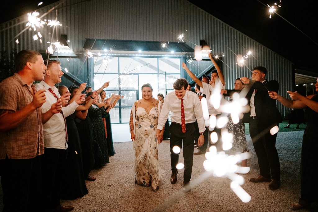 Bride and Groom holding hands for sparkler exit at night