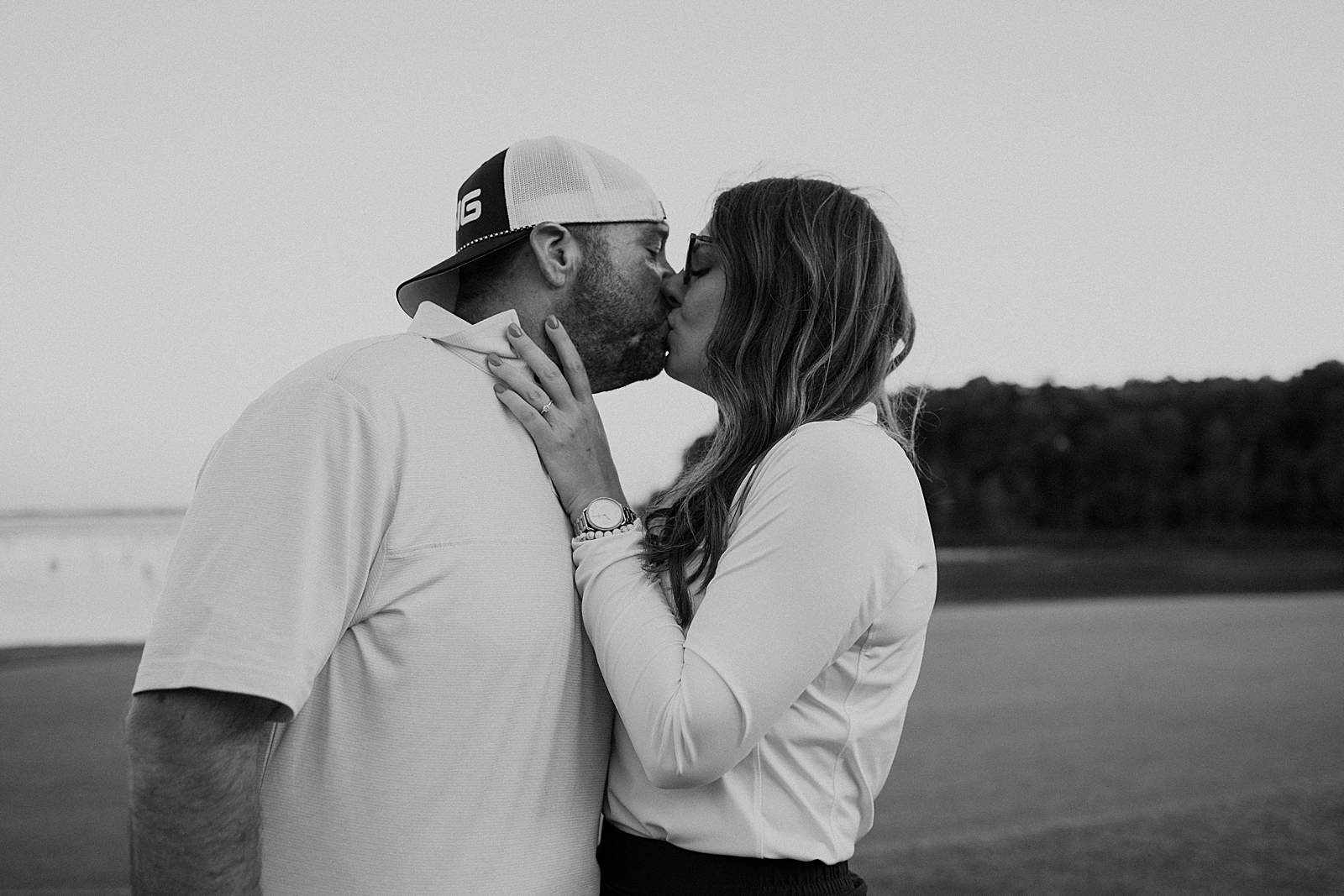 black and white photo of couple kissing on golf course
