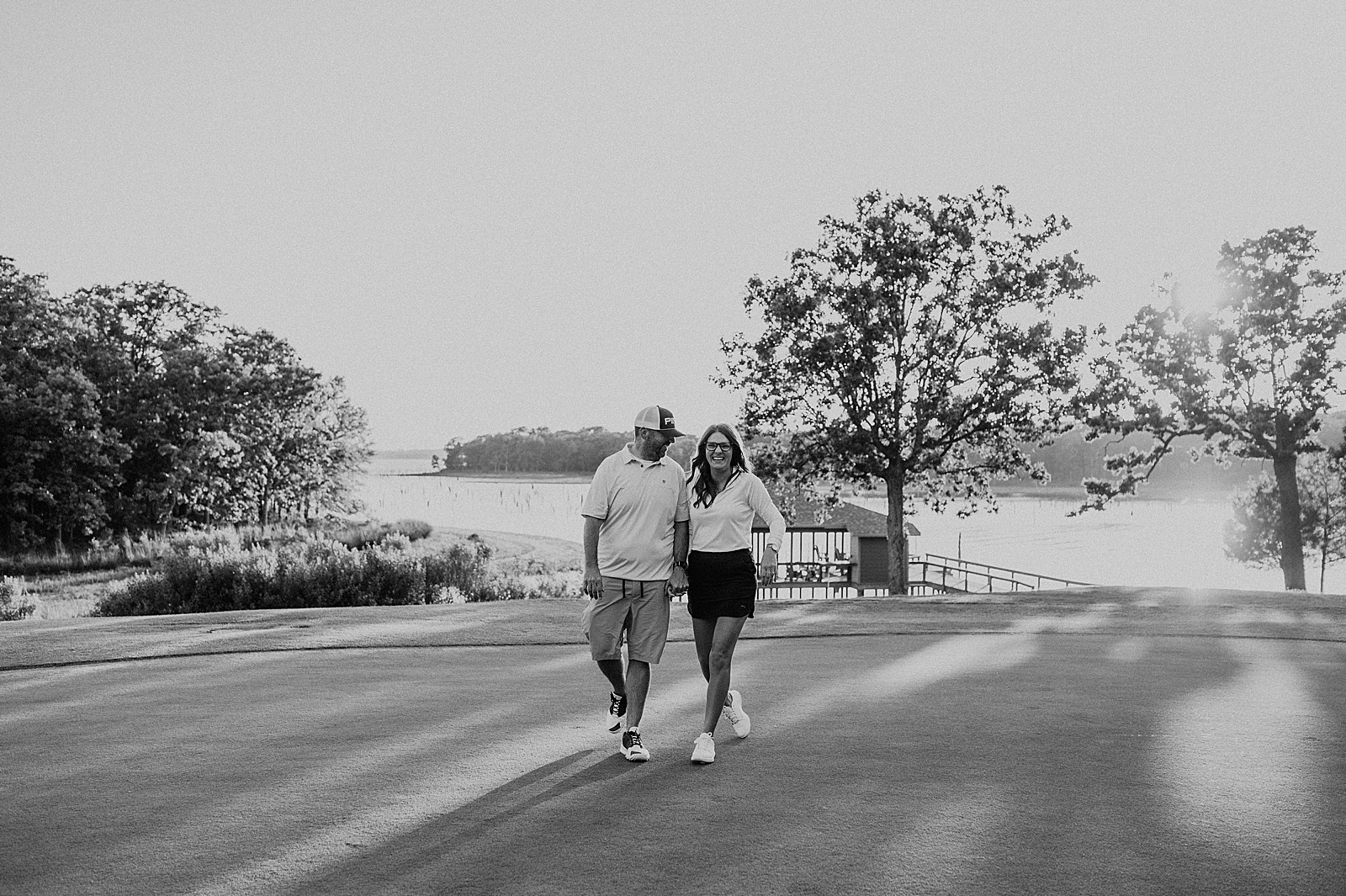 black and white photo of couple holding hands and walking on golf course