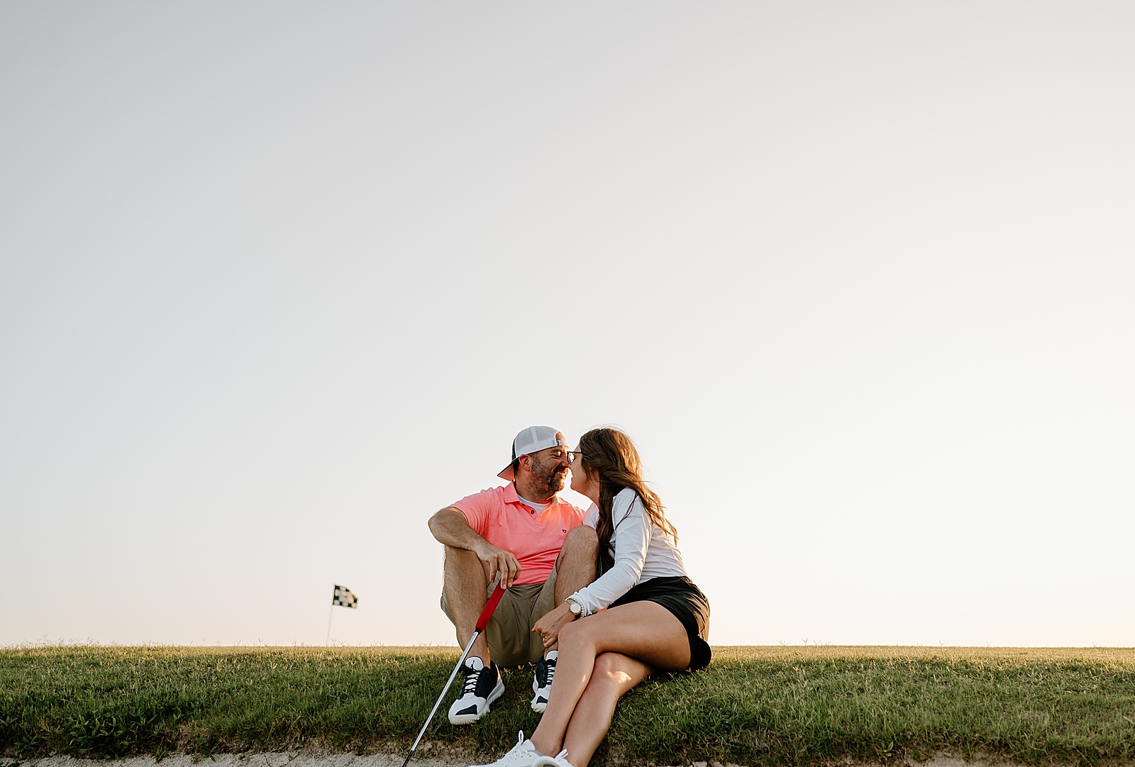 couple sitting on golf course with golf club